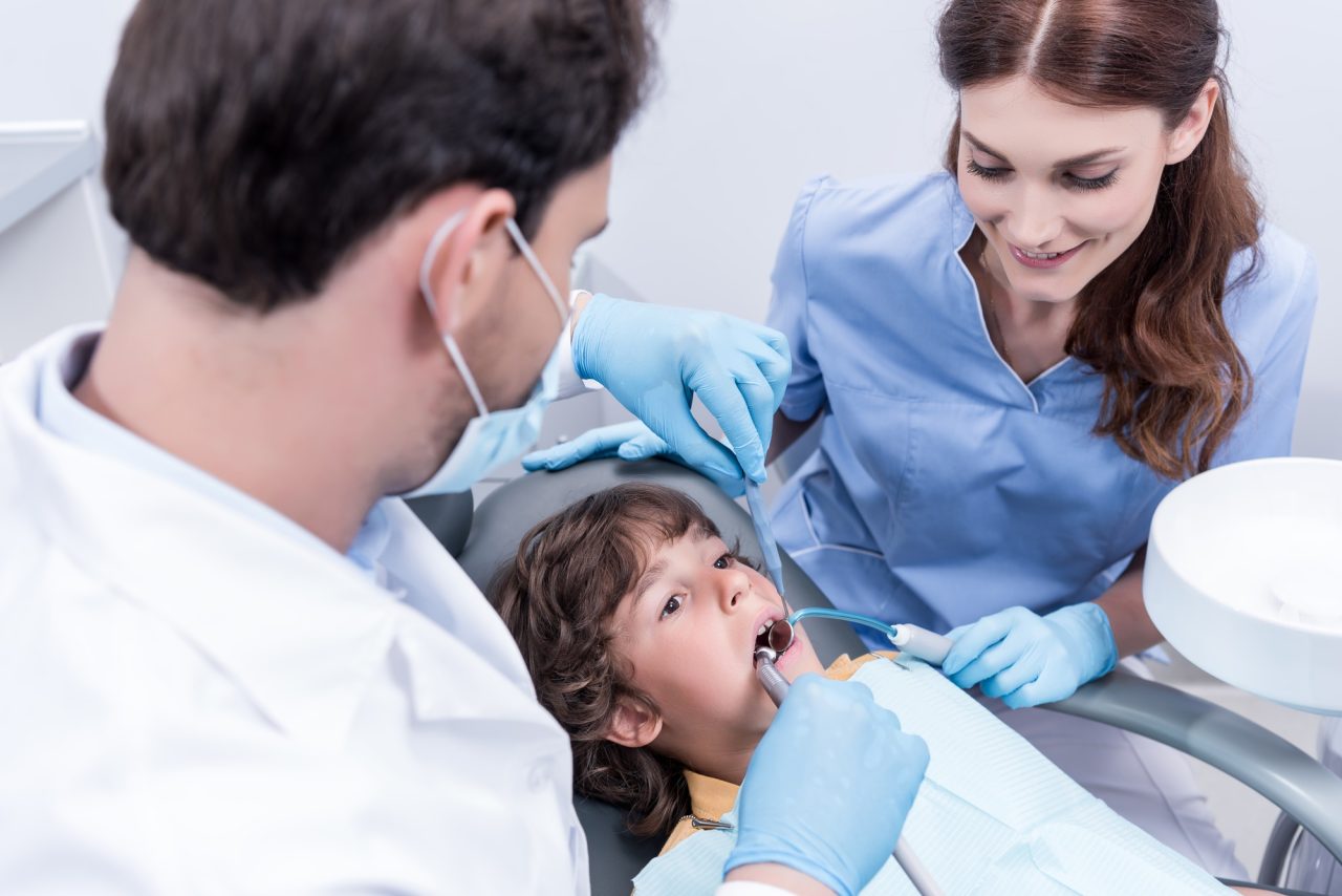 dentists treating teeth of little patient in dentist chair in hospital.jpg
